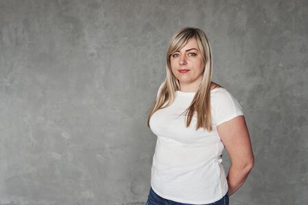 Casual clothes. Young white woman in the studio standing against grey background.の写真素材
