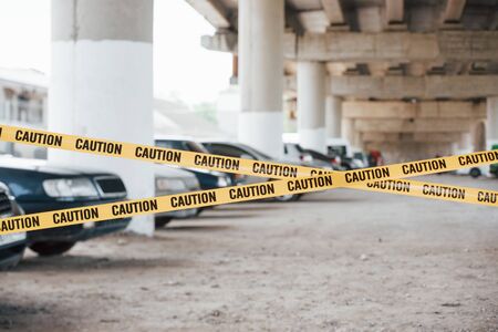 Big area. Yellow caution tape near the car parking lot at daytime. Crime scene.の写真素材