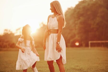 On soccer field. Mother and daughter enjoying weekend together by walking outdoors. Beautiful nature.の写真素材