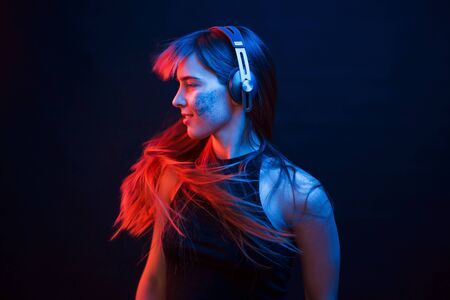 Photo im motion. Studio shot in dark studio with neon light. Portrait of young girl.の写真素材