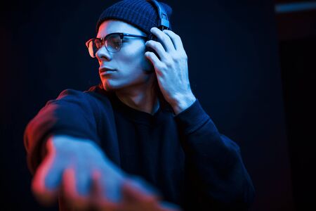 Party time. Studio shot in dark studio with neon light. Portrait of serious man.の写真素材