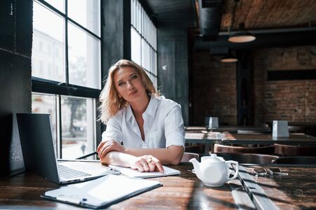 Psychologist listens to the patient. Businesswoman with curly blonde hair indoors in a cafe at daytime.の写真素材