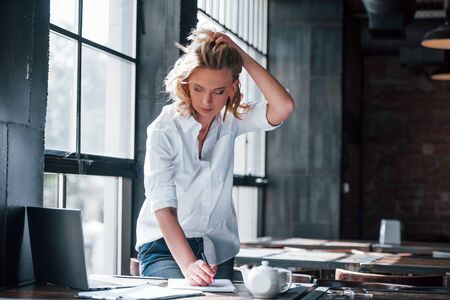 Need to hurry up. Businesswoman with curly blonde hair indoors in cafe at daytime.