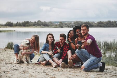 Please smile. Group of people have picnic on the beach. Friends have fun at weekend time.の写真素材