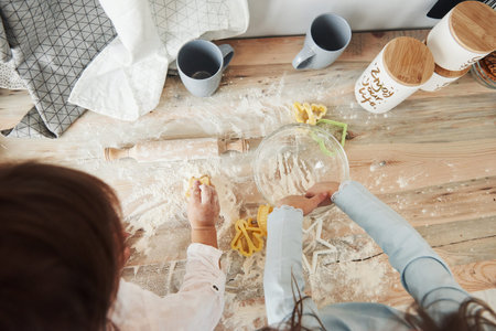 Top view of kids learning to prepare food from the flour with special formed instruments.