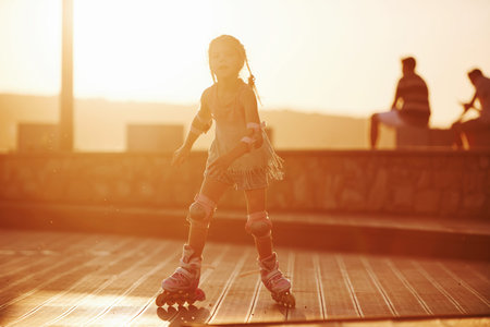 Happy cute kid riding on her roller skates. Unbelievable sunlight.