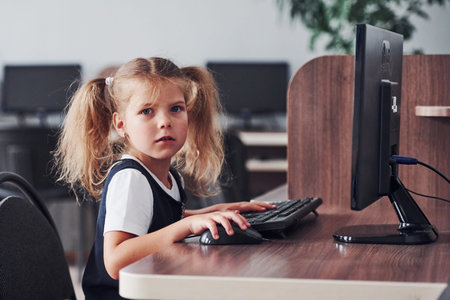 Young girl sitting by the computed and searching for information.
