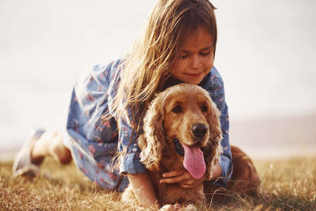 Front view of beautiful friendship of animal and human. Cute little girl have a walk with her dog outdoors at sunny day.の写真素材