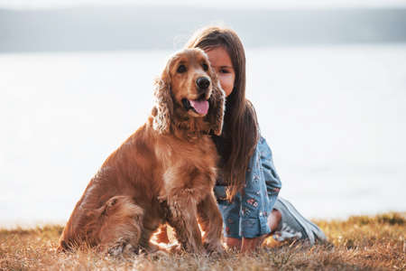 Cute little girl have a walk with her dog outdoors at sunny day.の写真素材