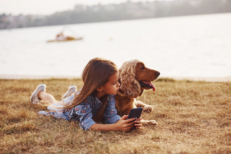 Swimming trasport behing on the lake. Cute little girl have a walk with her dog outdoors at sunny...