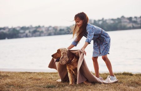 Using rog. Cute little girl have a walk with her dog outdoors at sunny day.