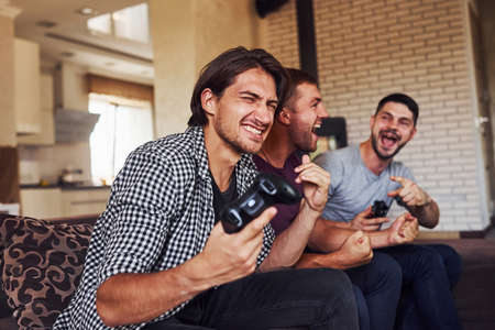 Group of friends have fun playing console game indoors at living room.の写真素材
