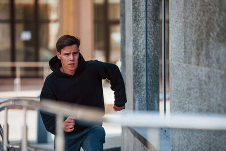 Front view of young runner in black clothes that is in the city.の写真素材