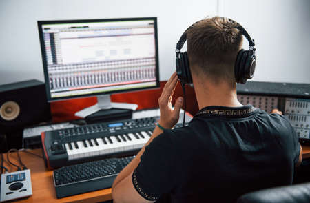 Sound engineer in headphones working and mixing music indoors in the studio.