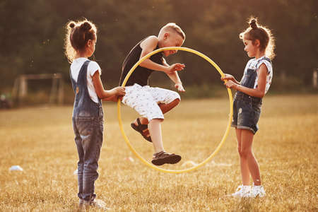 Jumping through the circle fitness tool. Kids having fun in the field.の写真素材