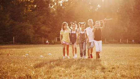 Group of kids having fun outdoors with red toy airplane in hands.の写真素材