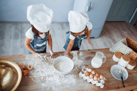 Top view. Family kids in white chef uniform preparing food on the kitchen.の写真素材