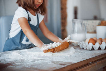 Close up view. Cute kid in white chef uniform preparing food on the kitchen.の写真素材