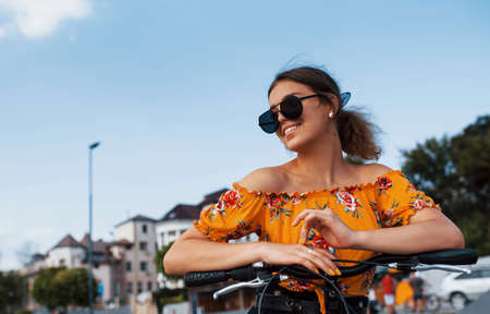 Portrait of positive young girl in sunglasses that stands with her bike.の写真素材