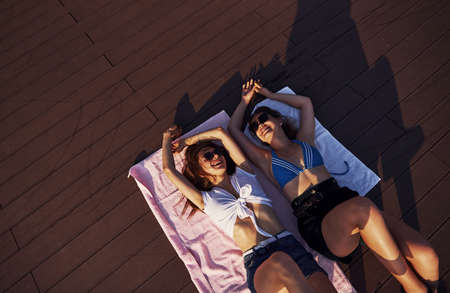 Top view of two girls on the beach that lying down on the ground and enjoying warm sunlight.の写真素材