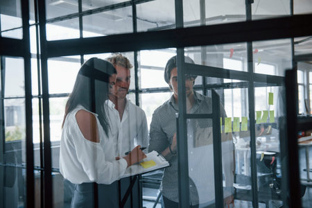 Yellow stickers is on the glass. Young business people in formal clothes working in the office.