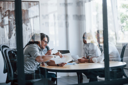 Some documents on the table and in hands. Young business people in formal clothes working in the...