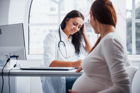 Pregnant woman have consultation with obstetrician indoors.