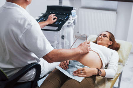Male doctor does ultrasound for a pregnant woman in the hospital.の写真素材