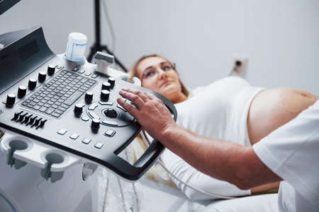 Male doctor does ultrasound for a pregnant woman in the hospital.の写真素材