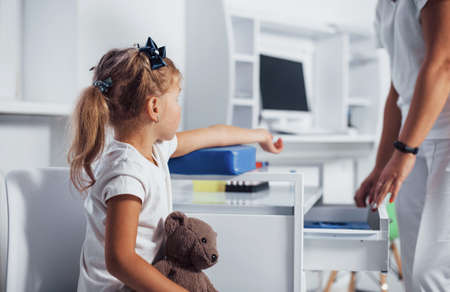 Preparation for blood sampling. Little girl with her toy in hands is in the clinic.の写真素材