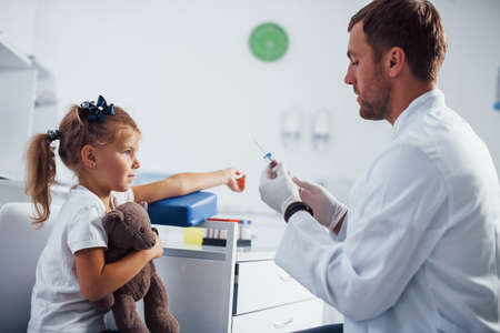 Blood sampling. Little girl with her teddy bear is in the clinic with doctor.の写真素材