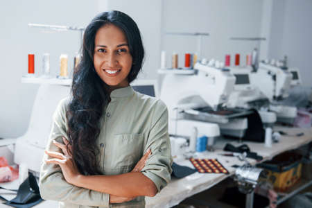 With arms crossed. Beautiful female worker is in the sewing factory.の写真素材