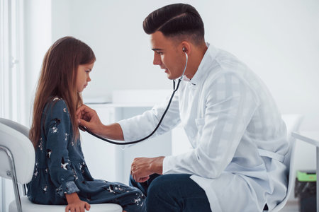 Young pediatrician works with little female visitor in the clinic.の写真素材