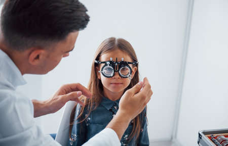 Testing vision. Young ophthalmologist is with little female visitor in the clinic.の写真素材