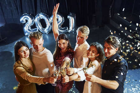 Knocking glasses. Cheerful group of people with drinks in hands celebrating new 2021 year.の写真素材