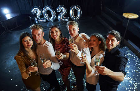 Cheerful group of people with drinks in hands celebrating new 2020 year.の写真素材