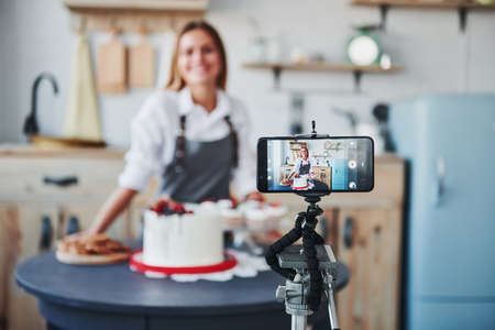 Woman makes delicious sweets and pie. Recording process by smartphone on tripod.の写真素材