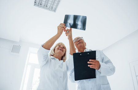 Senior man and woman doctors in white uniform examines x-ray of human legs.の写真素材