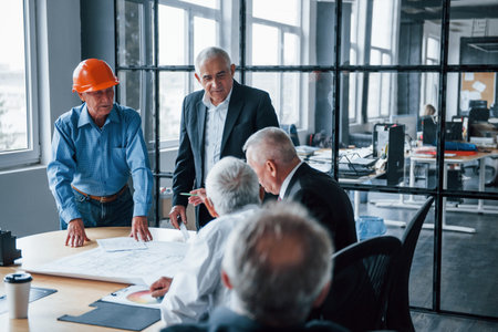 Aged team of elderly businessman architects have a meeting in the office.