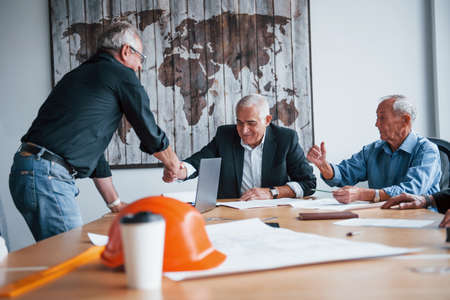 Doing handshake. Aged team of elderly businessman architects have a meeting in the office.の写真素材