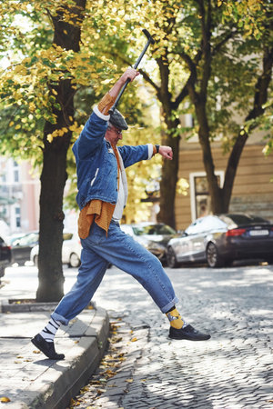 Happy stylish senior in fashionable clothes and in glasses have a walk and enjoying life.