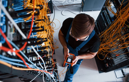 Top view of young man in uniform with measuring device that works with internet equipment and wires...