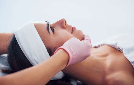 Close up view of woman that lying down in spa salon and have face cleaning procedure by cosmetologist in gloves.の写真素材