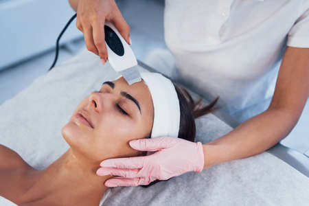 Using special device. Close up view of woman that lying down in spa salon and have face cleaning procedure.の写真素材