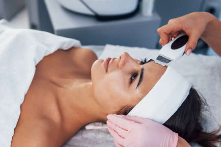 Using special device. Close up view of woman that lying down in spa salon and have face cleaning procedure.の写真素材