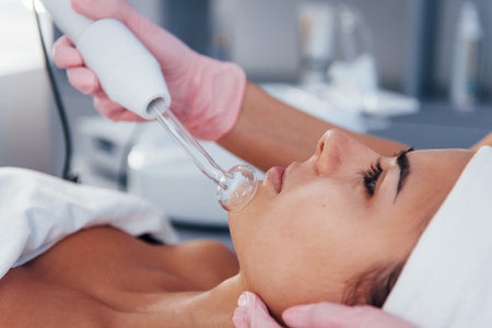 Close up view of woman that lying down in spa salon and have face cleaning procedure by using modern...
