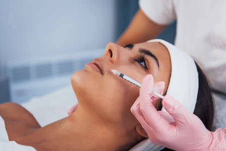 Close up view of woman that lying down in spa salon and have injection by the syringe into her face skin.の写真素材