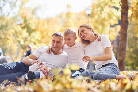 Cheerful young family lying down on the ground and have a rest in an autumn park together.の写真素材
