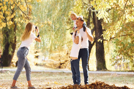 Cheerful young family have a walk in an autumn park together.