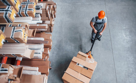 Top view of male worker in warehouse with pallet truck.